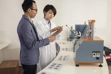 Technician explaining printing machine to manager in printing and packaging factory, China