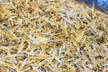 A heap of dried brown small fish inside of a seafood market