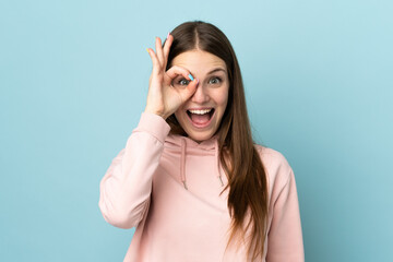 Fototapeta premium Young caucasian woman isolated on blue background showing ok sign with fingers