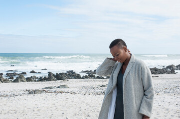 Young woman walking along beach, pensive expression