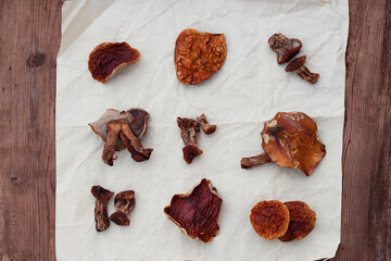 Dried mushrooms on paper on wooden background. Cooking ingredients. 