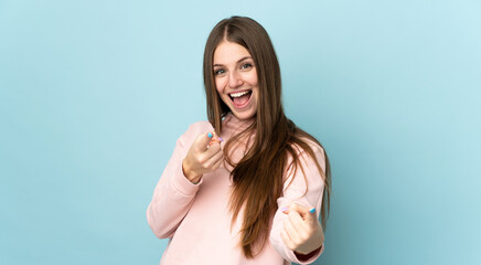 Young caucasian woman isolated on blue background surprised and pointing front