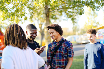 Obraz premium Group of friends in park, boy looking at smartphone, laughing