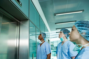 Three surgeons waiting for hospital elevator © Image Source Limited