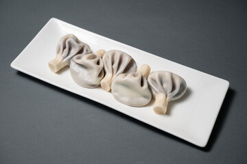 blueberry khinkali or georgian dumplings with meat on plate on black background