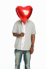 Mid adult man holding red balloon against white background