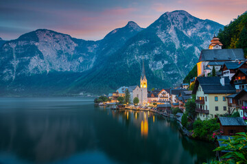 Hallstatt, Austria ; September 12, 2021 - A scenic picture postcard view of the famous village of Hallstatt reflecting in Hallstattersee lake in the Austrian Alps at dusk.	
