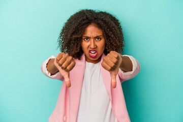 Young african american woman with curly hair isolated on blue background showing thumb down and expressing dislike.