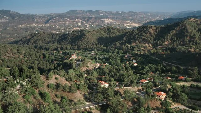 Cottages houses green forest mountain countryside village. Rural buildings homes in highland valley mount range. Nature background. Travel destinations. Beautiful landscape. Aerial view drone flight