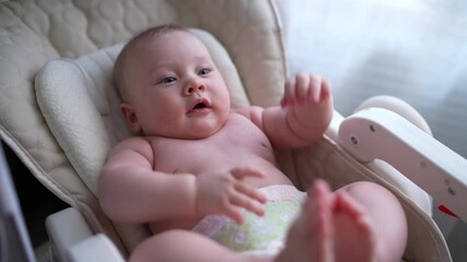 Cute newborn baby boy sitting in a white high chair next to a window. A joyful lifestyle of a happy mixed-race family. A young asian woman and active healthy baby with blue eyes in a rabbit costume