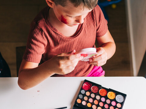 Crop boy with makeup on cheek looking in mirror