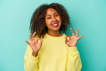 Young african american woman with curly hair isolated on blue background cheerful and confident...
