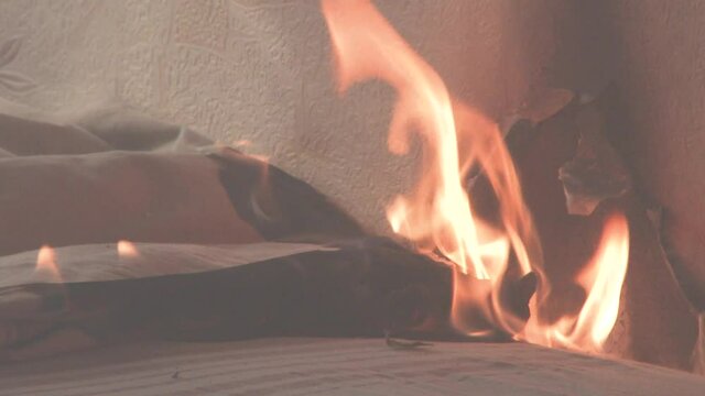 The bedroom is on fire with a lot of smoke. The bed, bedside table, plastic teapot, wallpaper and bookshelves are in flames in a residential home. Cinematic shot of aftermath of a two alarm fire 4k