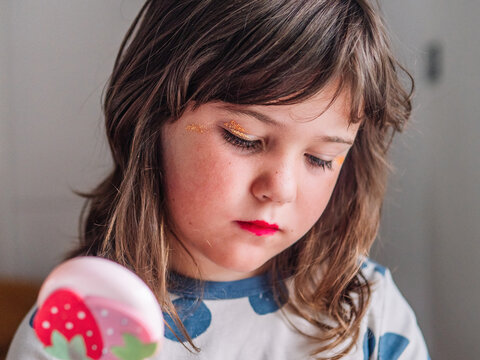 Girl applying glitter on face at home