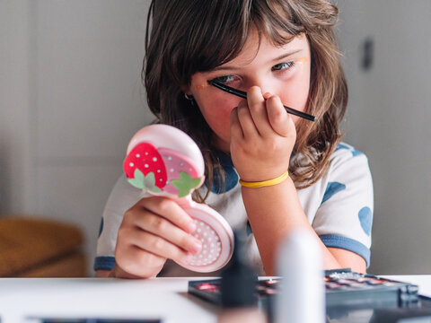 Girl applying glitter on face at home