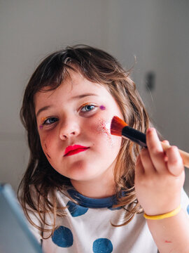Girl applying glitter on face at home