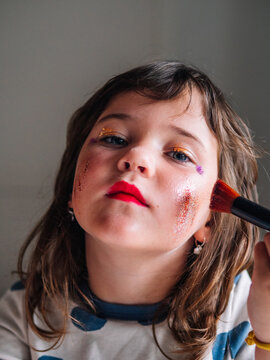 Girl applying glitter on face at home