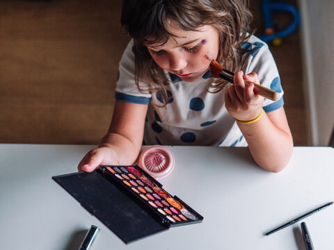 Girl applying glitter on face at home