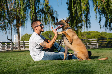 Man with Belgian Shepherd giving high five in park