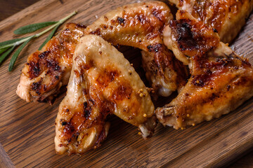 Grilled spicy chicken wings on a dark background with spices and herbs
