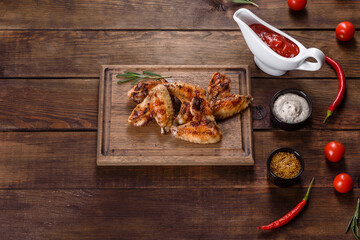 Grilled spicy chicken wings on a dark background with spices and herbs