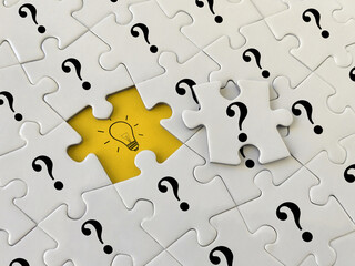 Creative idea or problem solving concept, question marks and light bulb icon on jigsaw puzzle,...