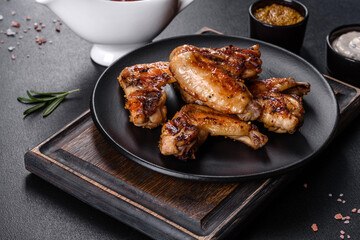 Grilled spicy chicken wings on a dark background with spices and herbs