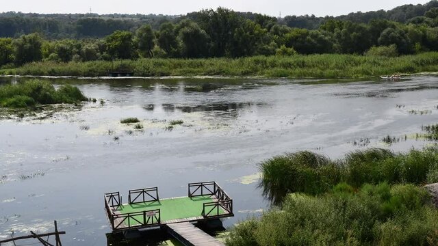 Time lapse water sport of inflated boats rafting by river Southern Bug with shores overgrown by reeds and bulrush. Landscape of Bug Gard islands in Ukraine. Plate with text - do not jump into water