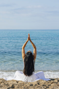Unrecognizable woman with praying hands practicing yoga on sea coast