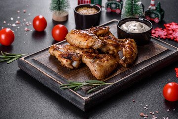 Grilled spicy chicken wings on a dark background with spices and herbs