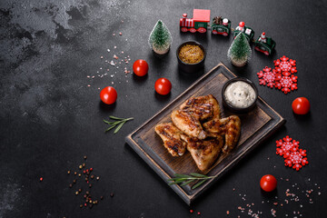 Grilled spicy chicken wings on a dark background with spices and herbs