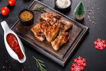 Grilled spicy chicken wings on a dark background with spices and herbs
