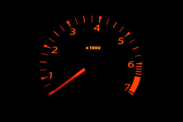 Car tachometer with orange scale on black background