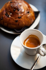 The table with sweets (pastries: croissant, cookies), white cups (mug) with hot black coffee (espresso), the saucer, the spoons at a local bar. Traditional Italian breakfast. Milan, Lombardy, Italy