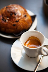 The table with sweets (pastries: croissant, cookies), white cups (mug) with hot black coffee (espresso), the saucer, the spoons at a local bar. Traditional Italian breakfast. Milan, Lombardy, Italy
