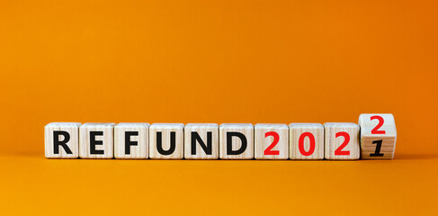 Planning 2022 refund new year symbol. Turned a wooden cube and changed words 'refund 2021' to 'refund 2022'. Beautiful orange background, copy space. Business, 2022 refund new year concept.