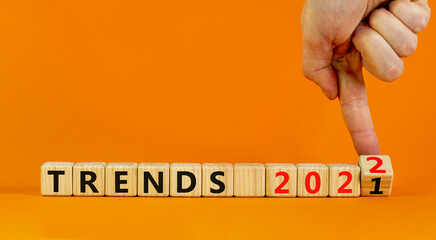 2022 trends new year symbol. Businessman turns wooden cubes and changes words 'Trends 2021' to 'Trends 2022'. Beautiful orange background, copy space. Business, 2022 trends new year concept.