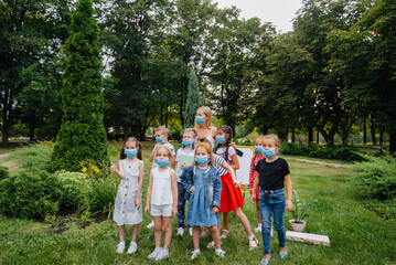 Obraz premium A class of masked school children is engaged in outdoor training during the epidemic. Back to school, learning during the pandemic