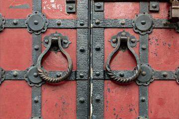 Red ancient gates with the metal fittings and the round doorknobs.