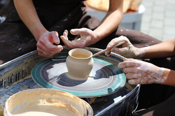 Master of ceramics teaches a student. the student sculpted a pottery. The master sculpts clay with his hands. Learning in the form of a game.