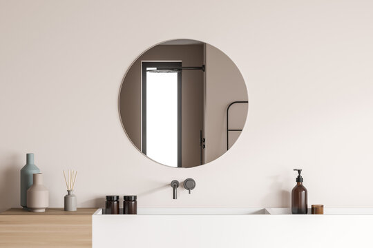 Round shower room mirror on beige wall with vanity