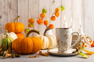 Autumn still life with cup of tea, pumpkins,flowers and candles on table.Thanksgiving day or halloween concept.