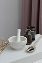 Mortar with spirulina pills and pestle. Spirulina pills in wooden spoon. Preparation of spirulina in pharmaceuticals.