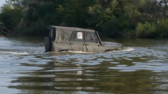 Teterev, Ukraine, 09.12.21. The car crosses the off-road competition river. Sport competitions. Car in the water. River stream. Race track. Off-road driving in mud. Vehicle in nature.