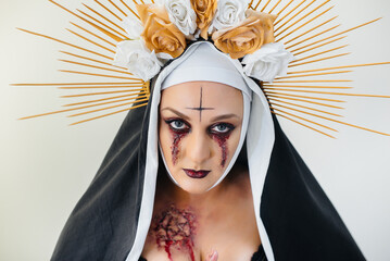 A young girl in a beautiful festive makeup and a scary nun costume for the Halloween holiday. Happy...