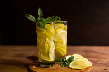 lemonade with mint leaves and lemon slices on a dark background