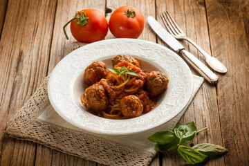 spaghetti with meatballs and tomato sauce over wooden background