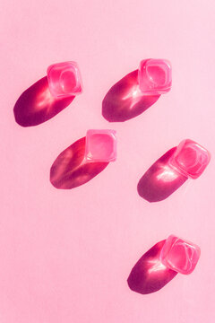 Creative layout with pink plastic cubes of ice at midday sun and hard shadows at the background. Summer mockup. Flat lay. Copy space.