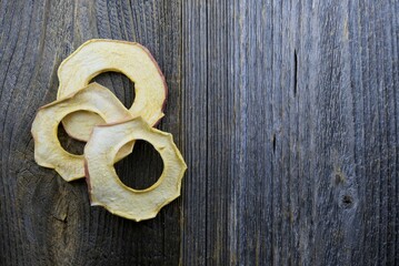 Top view of couple of dried apple rings on dark wooden background with copy space