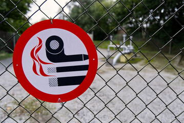 Red no smoking sign on chain link fence